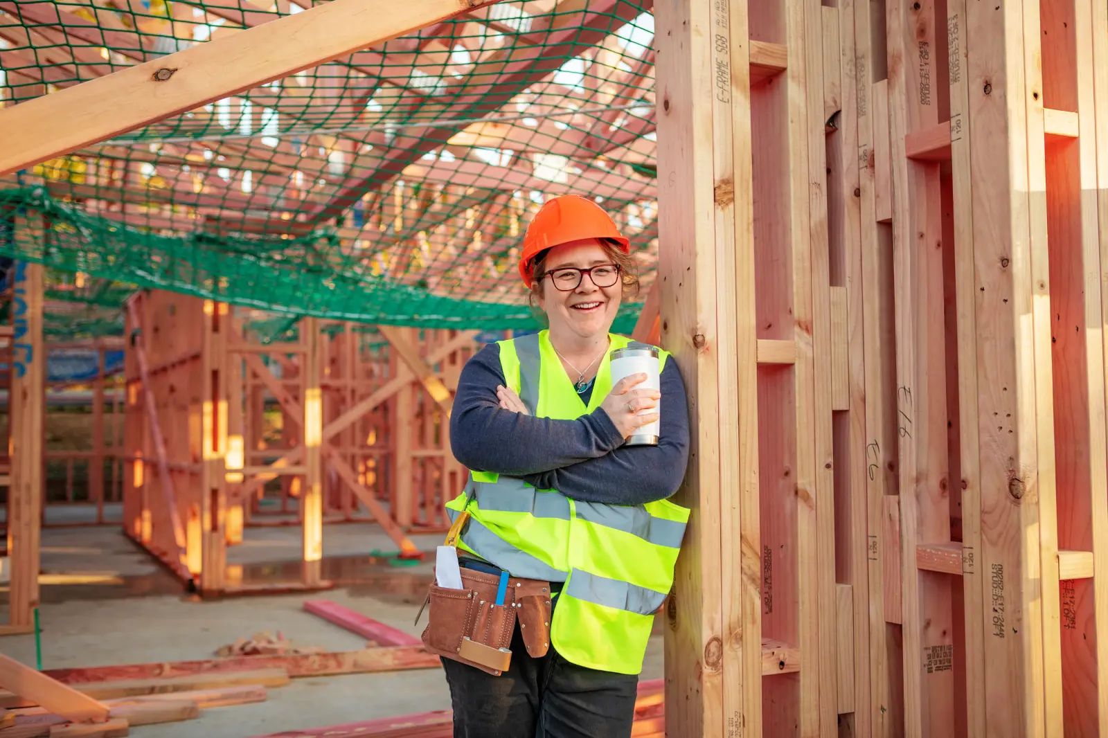 Tradie in safety vest leaning against a building frame